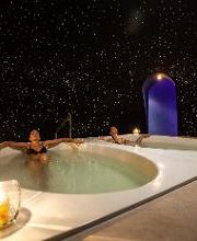 Personas en un jacuzzi bajo un cielo estrellado, con velas alrededor del borde.