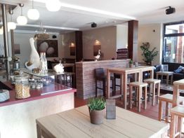 Helles Café mit Holzmöbeln, Dekor und viel natürlichem Licht durch große Fenster.