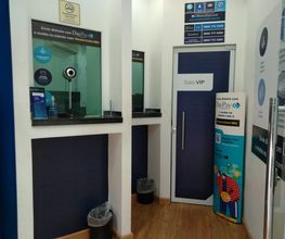 Recepção de agência com balcão de atendimento, mesinhas e porta marcada como "Sala VIP".