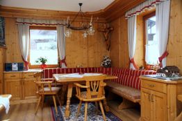 Holzvertäfeltes Esszimmer mit Eckbank, Tisch, Stühlen und dekorativen Elementen im Landhausstil.