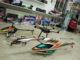 Elicotteri radiocomandati su un pavimento in un negozio di hobby, con scaffali sullo sfondo.