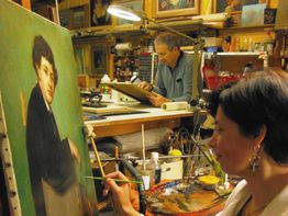 Un homme et une femme restaurent des peintures dans un atelier d'art.