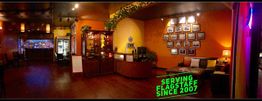 Cozy restaurant interior with warm lighting, wall photos, and text: "Serving Flagstaff Since 2007".