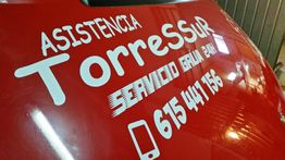 Texto blanco en vehículo rojo: "Asistencia Torres Sur, Servicio 24h, 615 441 156".