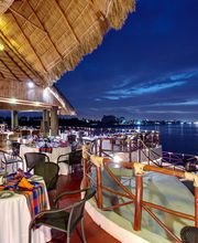 Restaurante junto al mar con mesas decoradas y cielo azul nocturno.