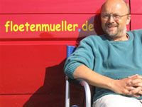 Ein Mann sitzt vor einem roten Hintergrund mit der Aufschrift "floetenmueller.de".