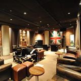 Sala de estar aconchegante com sofás e bandeira do Reino Unido na parede.