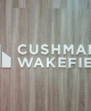 Logo de Cushman & Wakefield sobre un fondo de madera.