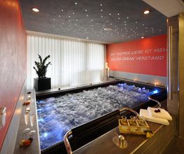 Whirlpool in einem modernen Raum mit roter Wand und Pflanzen. Entspannende Atmosphäre.