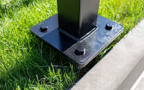 Bodenanker im Gras mit montiertem Pfosten einer freistehenden Seitenmarkise.