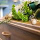 Bouquet of green and white flowers with a ribbon on a wooden coffin.
