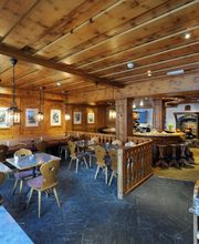 Gemütliches Restaurant mit Holzwänden, Tischen und Stühlen. Bilder an den Wänden.