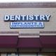 Dentistry sign with "Implants & Orthodontics" on a brick building facade above a maroon awning.
