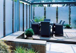 Moderne Terrasse mit Glasdach, Holzmöbeln und Pflanzen; idealer Ort zum Entspannen im Freien.