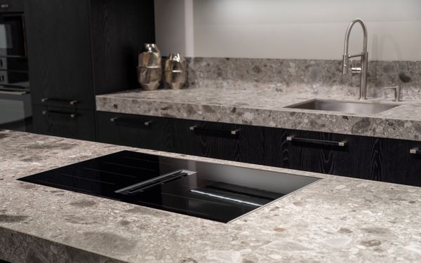 Encimera de cocina de piedra natural con placa de inducción integrada, superficie pulida y resistencia a calor y uso intensivo en entorno doméstico moderno.