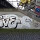 Graffiti unter Treppe: "Five" in Weiß mit Schatten und andere bunte Tags an der Wand.