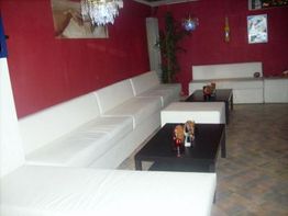 Weiße Sofas in einem Raum mit roten Wänden, dunklen Tischen und dekorativen Leuchten.