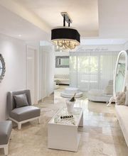 Sala moderna con sillones grises, mesa blanca, espejo decorativo y lámpara colgante.