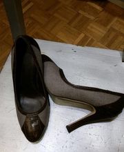 Braune High Heels auf einem Holzstuhl, Parkettboden im Hintergrund.