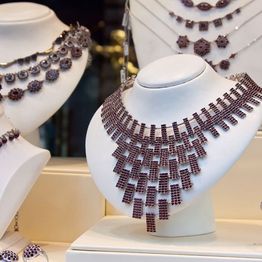 Elegant necklaces displayed on white busts in a jewelry shop.