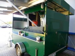 Grüner Imbisswagen mit offenem Dach, Kaffeebechern und Zubehör auf der Theke.
