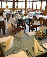 Elegantes Restaurant mit gedeckten Tischen, blauen Tischdecken und gefalteten Servietten.