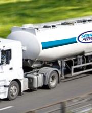 Camion cisterna bianco su strada, logo "Serreti Petroli" sul lato. Sfondo verde sfocato.