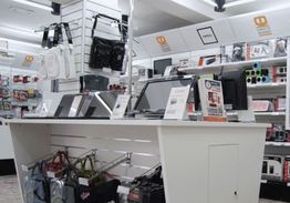 Negozio di elettronica con laptop in esposizione e borse appese.