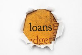 Torn paper revealing the word "loans" on a textured orange background.