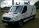 Weißer Mercedes-Transporter mit Aufschrift und Lichtanlage, geparkt auf einer Baustelle.