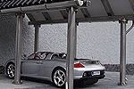 Silbernes Auto parkt unter einem modernen Carport mit Säulen auf grauem Hintergrund.