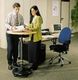 Zwei Personen stehen an einem Stehtisch im Büro und schauen sich gemeinsam Dokumente an.