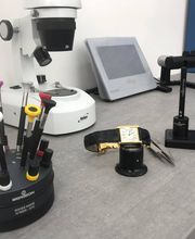 Banco con strumenti per la riparazione di orologi, inclusi cacciaviti e lente d'ingrandimento.