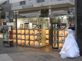 Schaufenster eines Juweliergeschäfts mit Uhren und einem Hochzeitskleid auf einer Puppe.