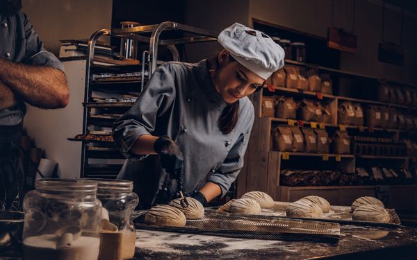 Bäckerin präpariert Brot bevor es gebacken wird.