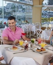Familia disfrutando de un desayuno en restaurante con vista al mar.