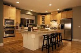 Modern kitchen with wooden cabinets, island, bar stools, and stainless steel appliances.