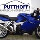 Blaues Motorrad vor Werbeschild: PUTTHOFF FAHRZEUG-VEREDELUNG.