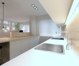 Cocina moderna con encimera blanca, fregadero, vitrocerámica y luces empotradas en el techo.