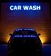 Auto vor einem Schild mit der Aufschrift "CAR WASH" in blauer Neonbeleuchtung.