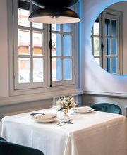 Mesa de restaurante elegante con flores, bajo una lámpara moderna y un espejo redondo en la pared.