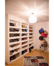 Begehbarer Kleiderschrank mit Regalen voller Schuhe und Taschen, Teppich auf dem Boden.