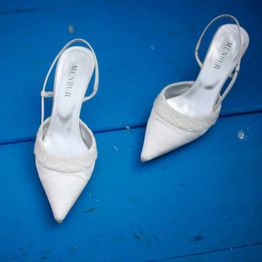 Weiße High Heels auf blauem Hintergrund, nebeneinander positioniert.