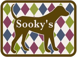 Brauner Hund vor farbigem Rautenmuster mit dem Schriftzug „Sooky's“.