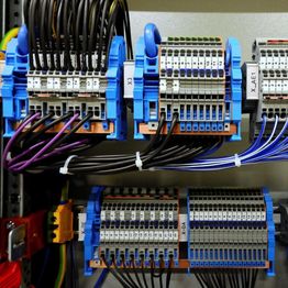 Close-up of a wiring terminal block in an electrical panel, featuring multiple cables and connectors.