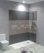 Ducha moderna con azulejos decorativos y un inodoro, en un baño de diseño sencillo y minimalista.