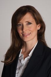 Eine Frau in Business-Kleidung lächelt in die Kamera.