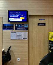 Agência de câmbio com cadas de atendimento, cartazes e cadeiras pretas no interior.