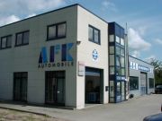 Zweistöckiges Gebäude mit AFK Automobil-Logo, Glasfassade und blauen Fenstern unter blauem Himmel.