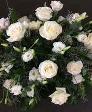 Arreglo de rosas blancas con follaje verde sobre un fondo oscuro.